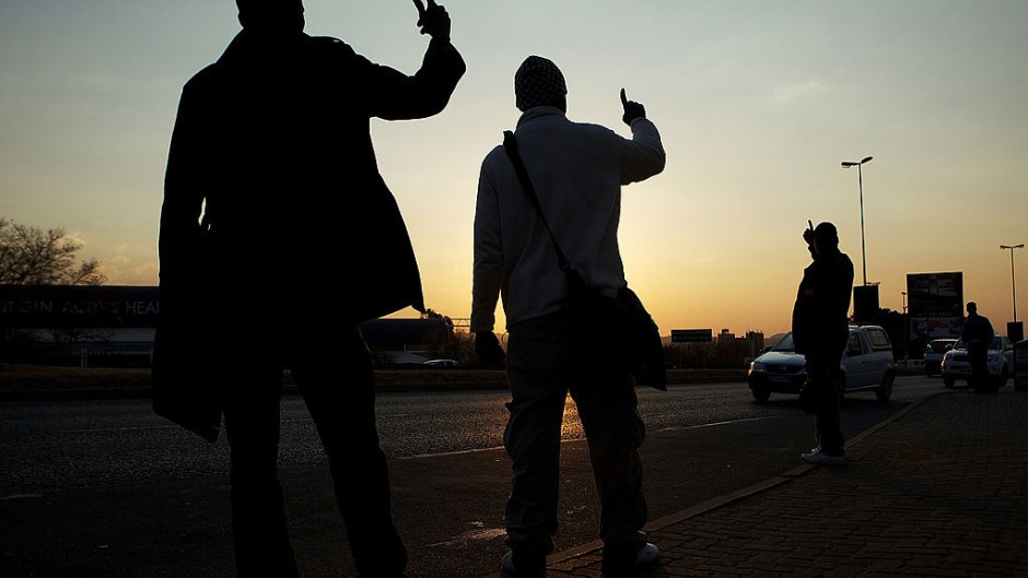 File: Commuters hold up their hands to signal to oncoming taxis what their desired destination is. Morne De Klerk/Getty Images