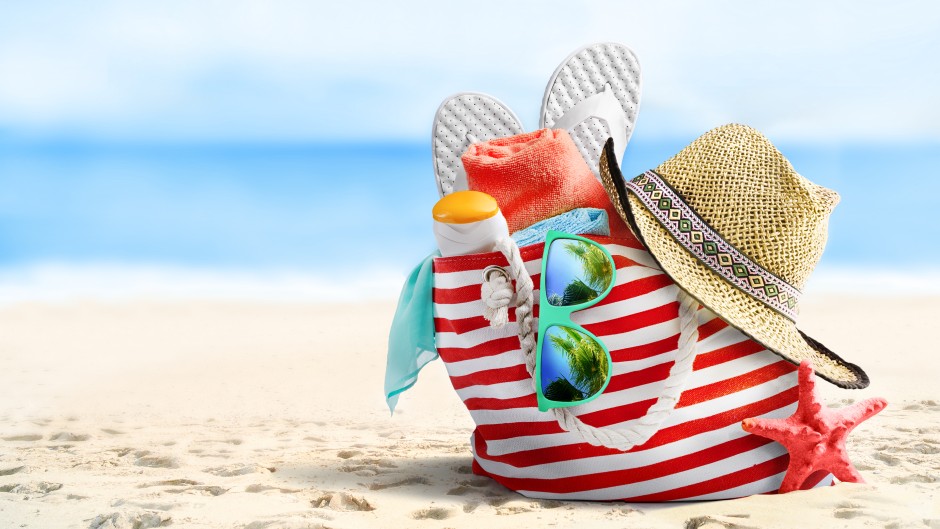 File: Beach bag, straw hat, flip flops, sunglasses and starfish on sandy beach. Getty Images/igoriss