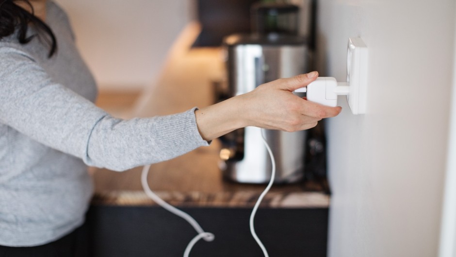 File: A woman plugging in a mobile phone charger on wall. GettyImages/Maskot