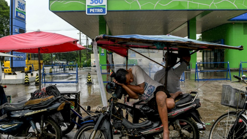 A man sleeps on his motorcycle as motorists queue to fill their vehicles at a petrol station in Yangon. AFP