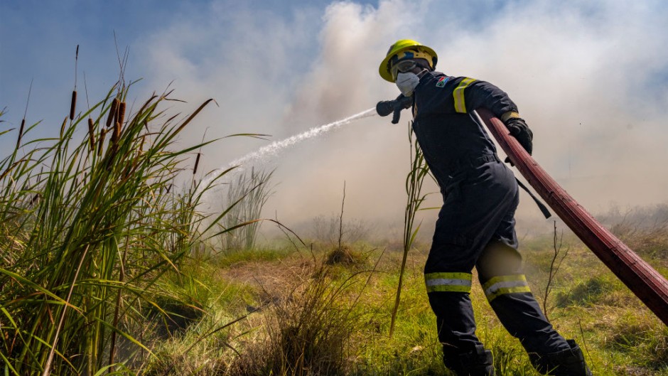 File: Firefighters try to extinguish a veld fire. Jaco Marais/Die Burger/Gallo Images via Getty Images