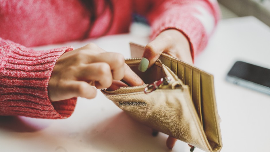 File: A woman looking for money in a wallet. GettyImages/Carol Yepes