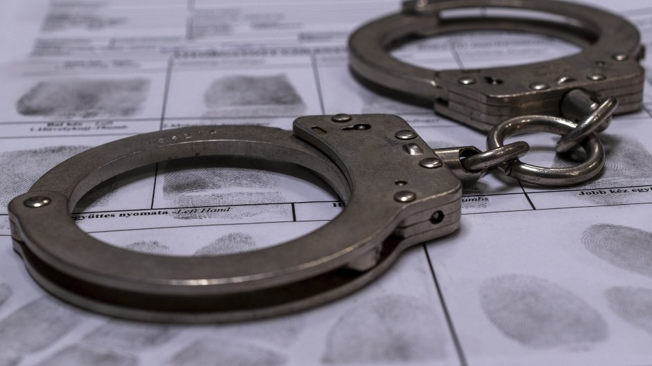 File: Handcuffs and a fingerprint card. GettyImages/Daniel Tamas Mehes