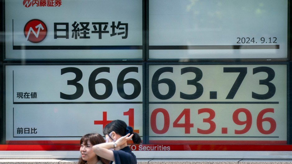 Pedestrians stand in front of an electronic quotation boards displaying the Nikkei index on the Tokyo Stock Exchange. AFP/Kazuhiro Nogi