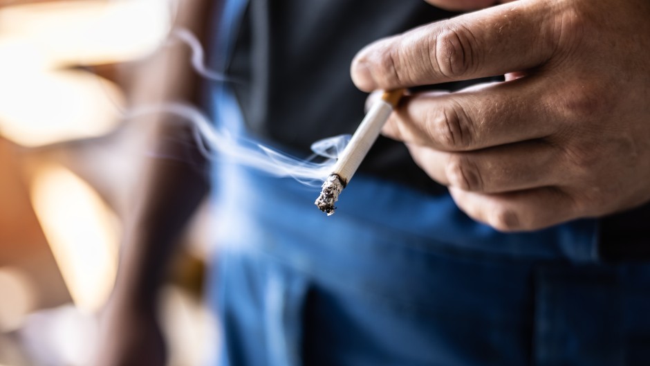 File: A man holding a smoking cigarette in his hand. GettyImages/SimpleImages