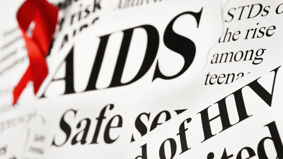 File: A red awareness ribbon on AIDS-related newspaper headlines. GettyImages/RapidEye