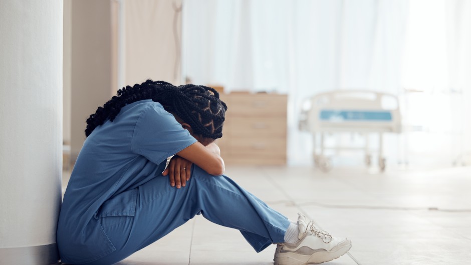 File: A nurse suffering from depression and burnout sitting on the floor. GettyImages/Jacob Wackerhausen