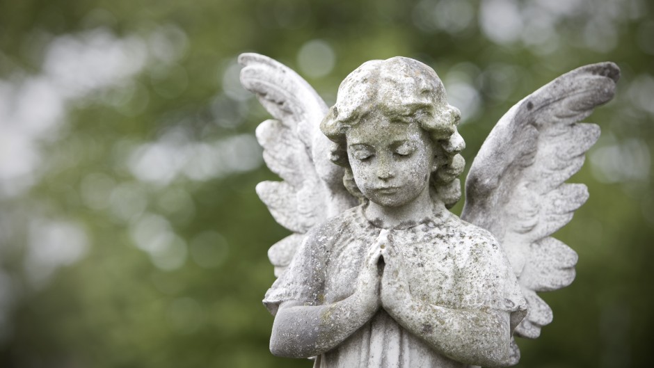 Stone cherub praying in graveyard. GettyImages/richardwatson