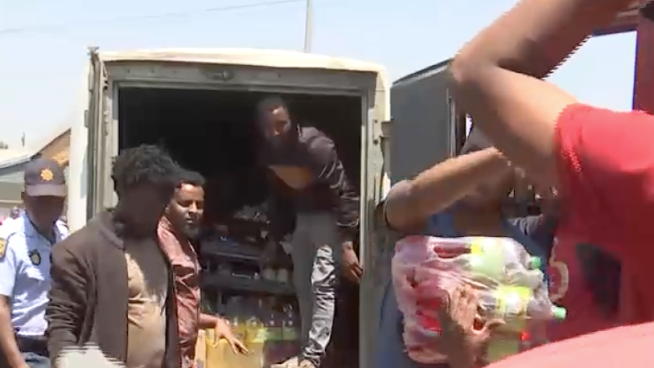 Police keeping an eye on people as they remove food from a spaza shop. 