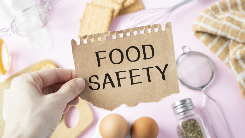 File: A person holds a card with the text FOOD SAFETY. GettyImages/Inna Kot