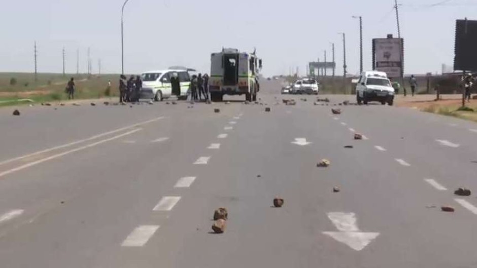 Police vehicles at a protest in Lenasia.