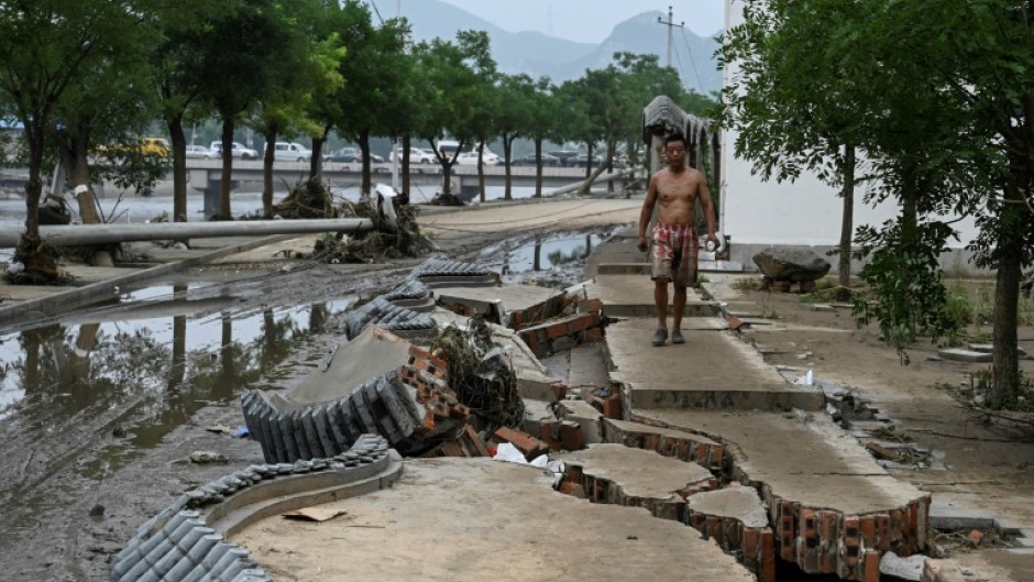 A resident walks on a broken wall after flooding battered swathes of northern China 