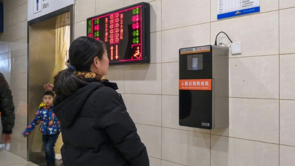 An automatic toilet paper dispenser (R) at a Chinese railway station uses facial recognition technology. China is drafting rules on use of the technology