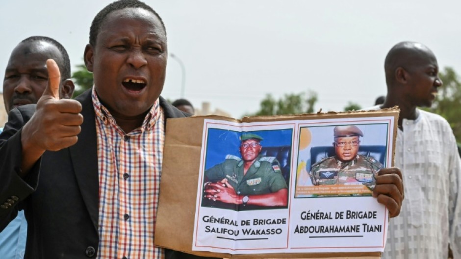 A supporter of the coup holds up a photo of new strongman General Abdourahamane Tiani at a rally in Niamey on Sunday