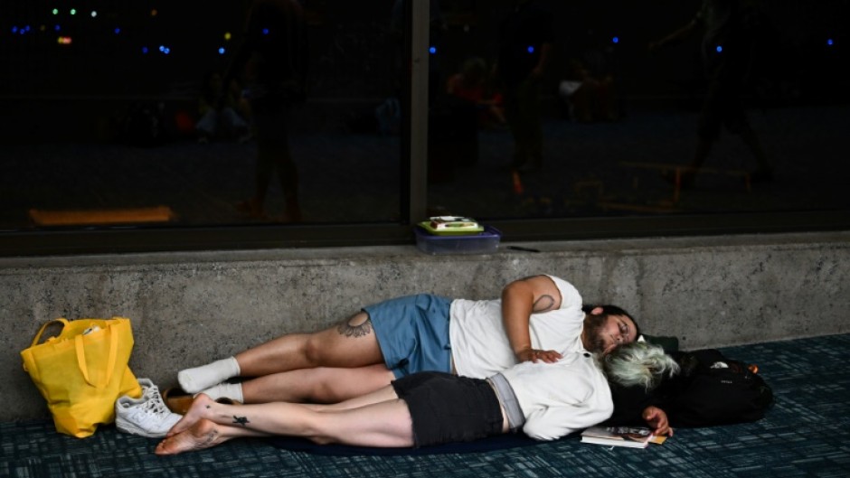 Passengers try to sleep on the floor of Kahului Airport  while waiting for delayed and canceled flights on August 9, 2023 