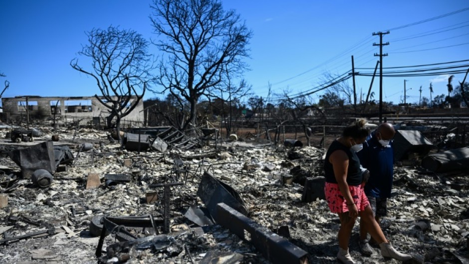 Residents look for belongings through the ashes of their family’s home