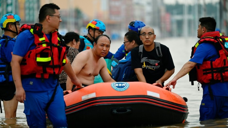 Rescuers wade in a flooded road as they evacuate residents following heavy rains in Zhuozhou, in northern China's Hebei province on August 2, 2023