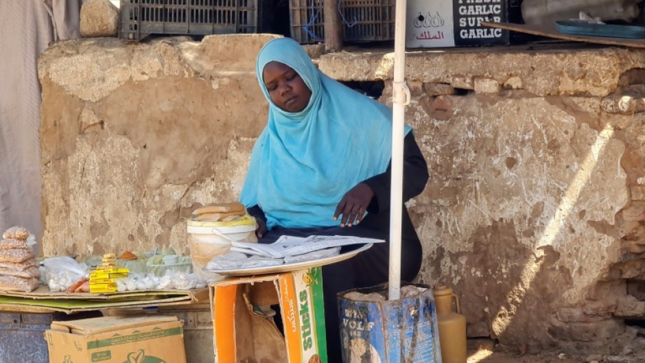 A woman sells foodstuffs at a stall in a Khartoum street as she tries to make a living amid the near-daily air strikes and artillery bombardments