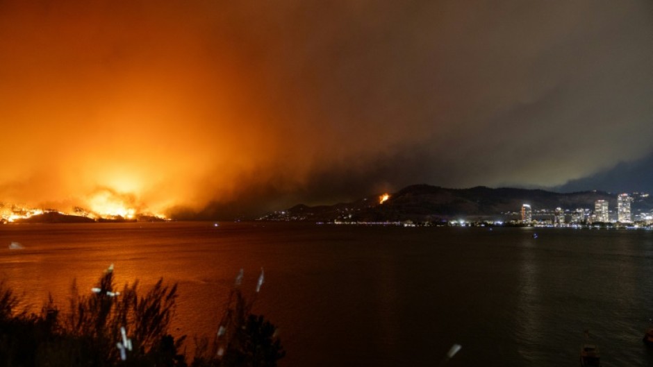 The McDougall Creek wildfire burns in the hills outside West Kelowna, British Columbia, on August 17, 2023, as seen from the nearby city of Kelowna