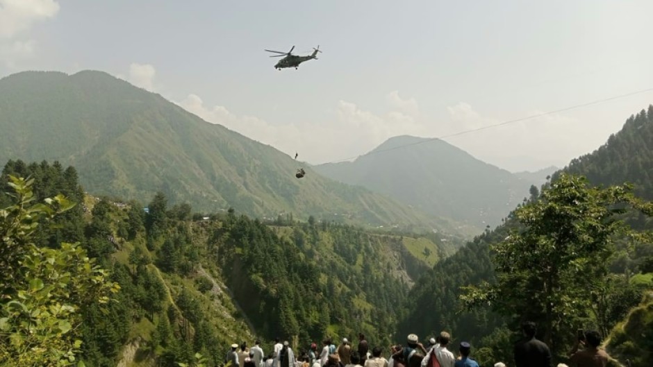 Anxious locals watch as a helicopter flies near the stranded cable car in northern Pakistan