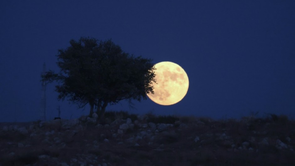 A picture taken from the Israeli city of Rosh Haain shows the 'Blue Moon' rising over the West Bank, on August 30, 2023