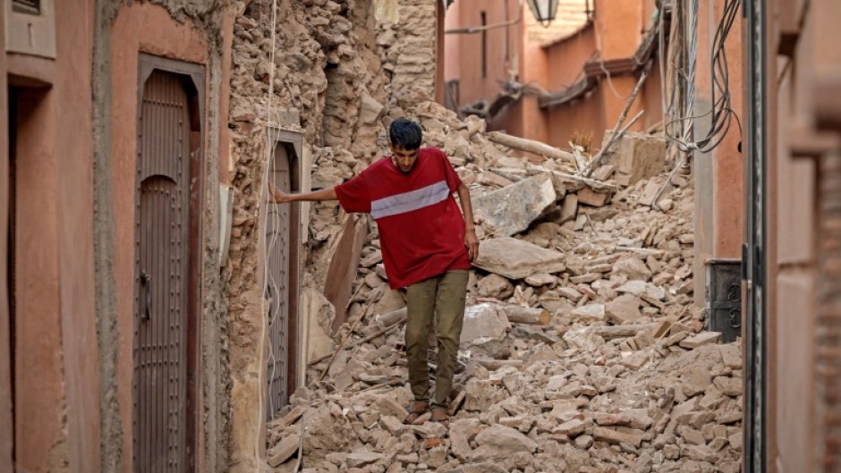 A Marrakesh resident clambers over the rubble of a home blocking one of the city's historic alleyways