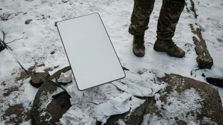 A Ukrainian serviceman stands next to the antenna of a Starlink satellite-based broadband system in Bakhmut in February 2023