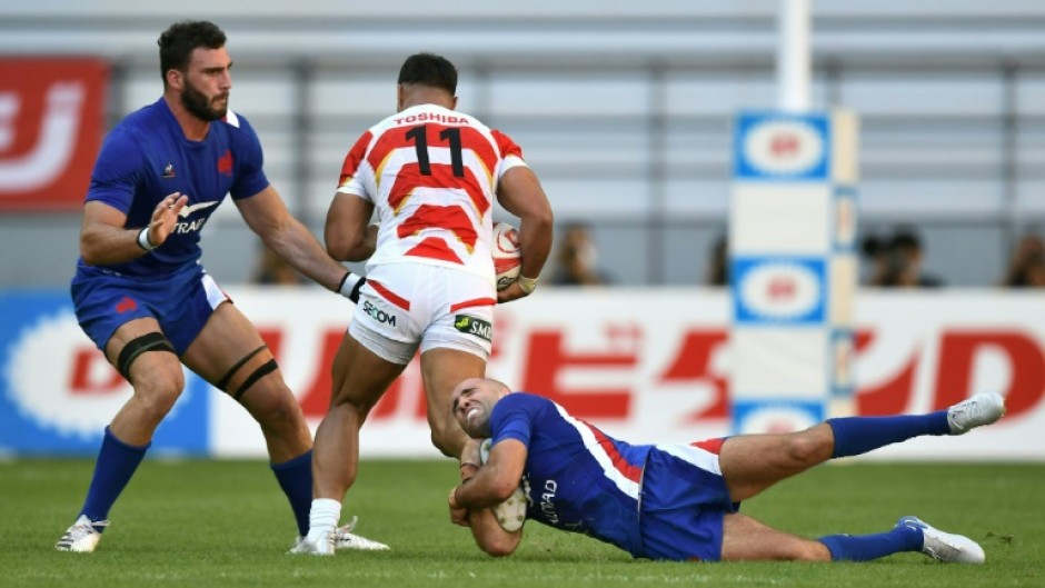 France's Maxime Lucu (R) and Charles Ollivon (L) tackle Japan's Siosaia Fifita (C)