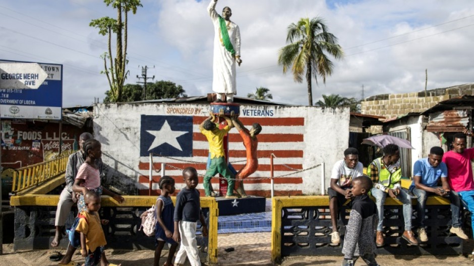 People gather around a monument honoring the President of Liberia George Weah in Clara town, Monrovia