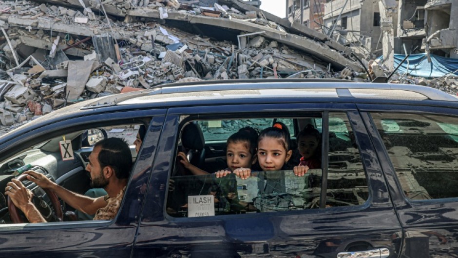 Palestinians drive amid the rubble of buildings destroyed in an Israeli air strike in Rafah, on the southern Gaza Strip 