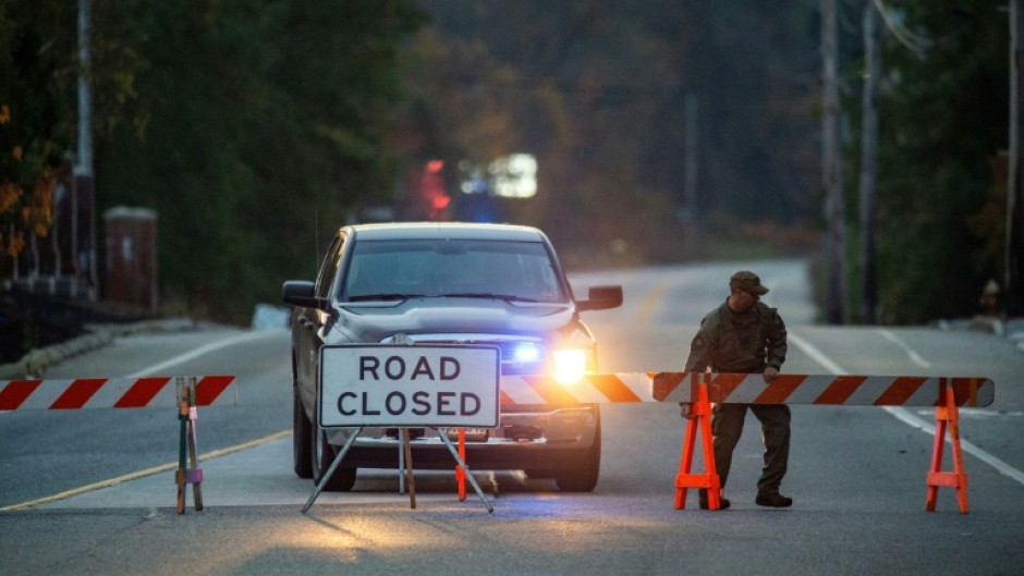 A law enforcement official blocks the road to Schemengees Bar where the shooting took place in Lewiston, Maine