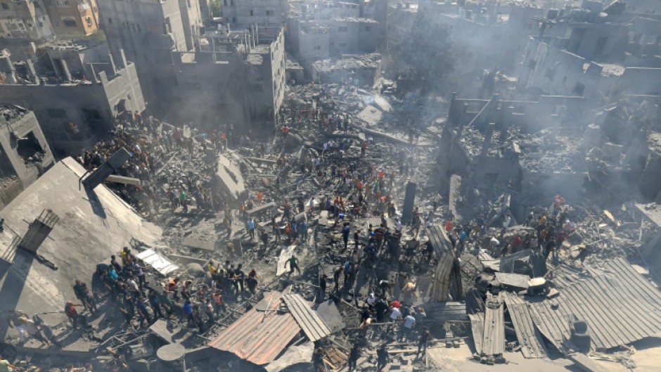 People search for survivors and the bodies of victims through the rubble of buildings destroyed during Israeli bombardment, in Khan Yunis in the southern Gaza Strip on October 26, 2023