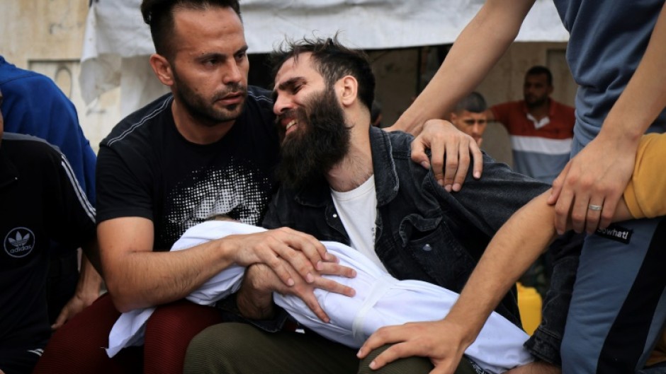 A father mourns his child killed in an Israeli strike on Khan Yunis in the southern Gaza Strip, before his burial on October 29, 2023