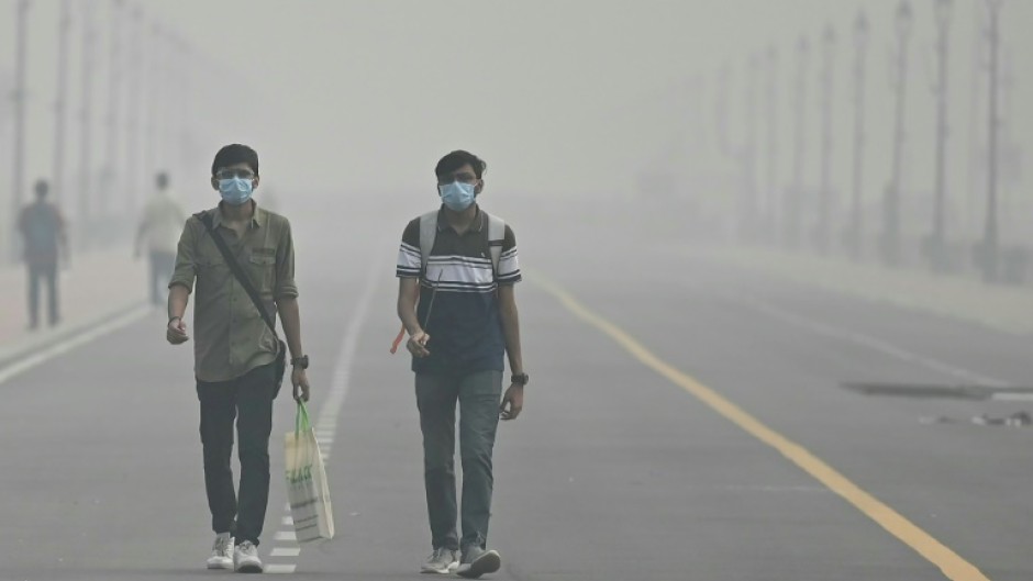 Smog-choked: People wearing face masks walk along the Kartavya Path in New Delhi on Sunday