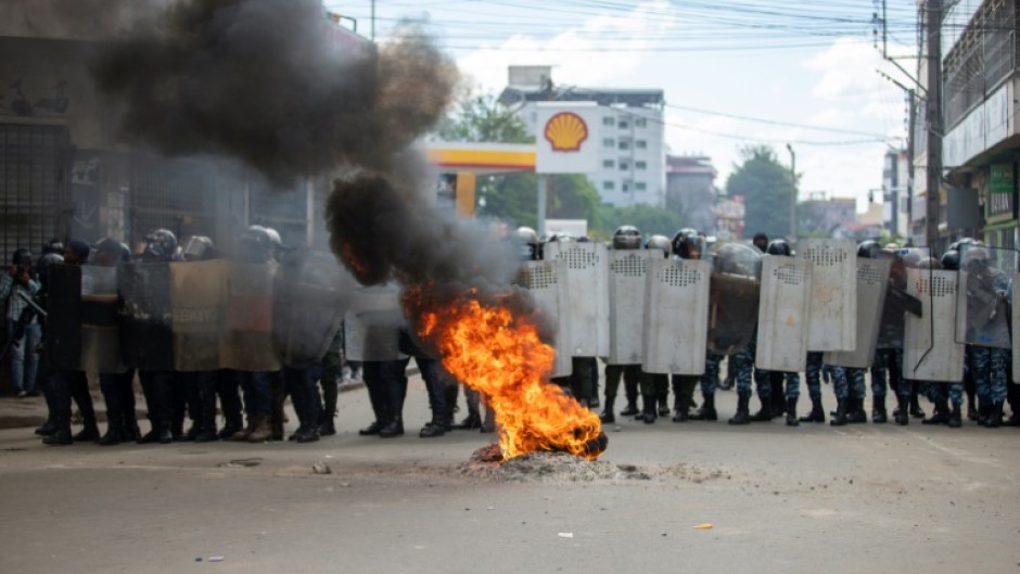 Anti-riot police use shields to protect themselves from stone-throwing protesters in Antananarivo