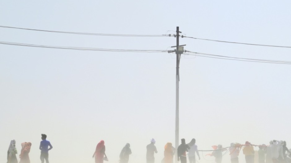 People walk through a dust storm on a hot summer day in India in April 2023.