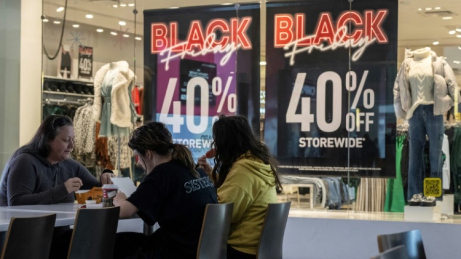 A family eats lunch near a store advertising a Black Friday sale at the Pentagon City Mall in Arlington, Virginia