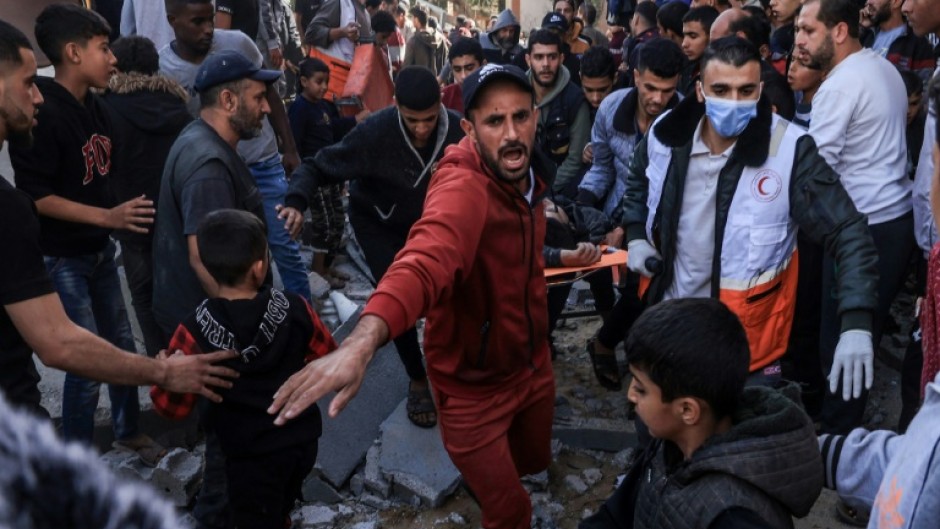 A Palestinian medic and civilians carry an injured man after an Israeli strike on Rafah, in the southern Gaza Strip, ahead of an expected pause in fighting