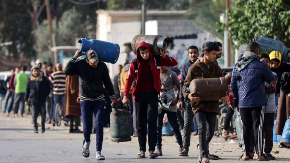 Palestinians in Rafah, the southern Gaza Strip, carry empty canisters to be filled with cooking gas from a shipment that entered as increased aid flows under the hostage release deal