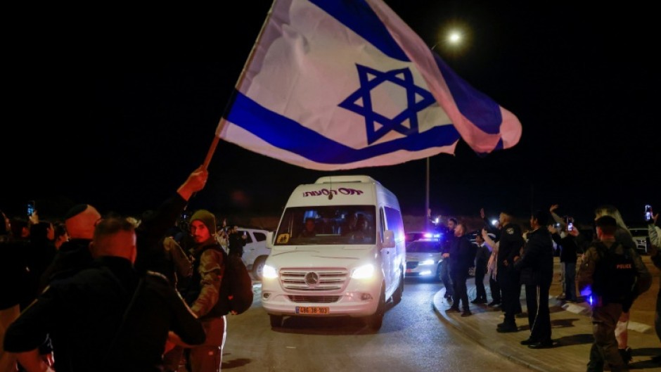 A man waves an Israeli flag as a vehicle carrying two newly freed women hostages with Russian citizenship passes in southern Israel on November 29, 2023