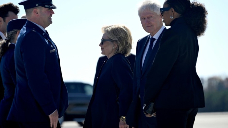 Former US Secretary of State Hillary Clinton, former US President Bill Clinton, and former US First Lady Michelle Obama are greeted upon arrival at Dobbins Air Reserve Base as they arrive to attend a tribute service for former US First Lady Rosalyn Carter