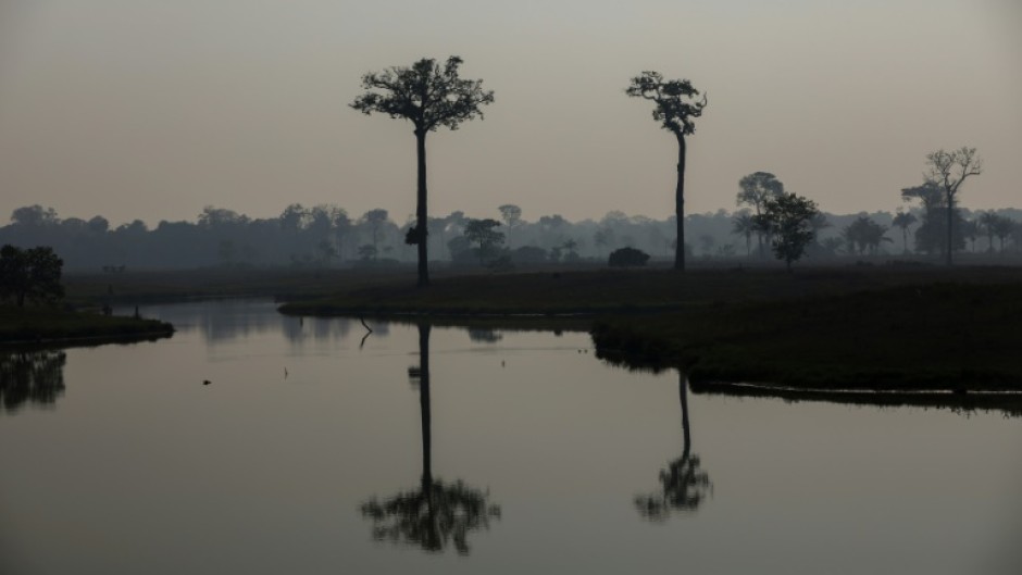 Smoke from illegal fires lit by farmers rises over a river in Careiro, Amazonas state, in September 2023