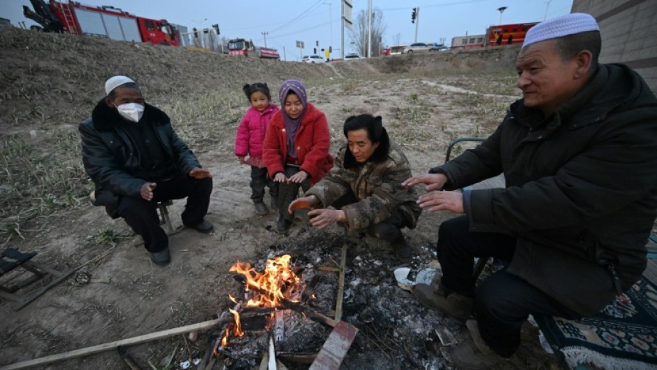 People huddle around a fire after an earthquake in northwest China’s Gansu province killed 131 people and damaged thousands of buildings