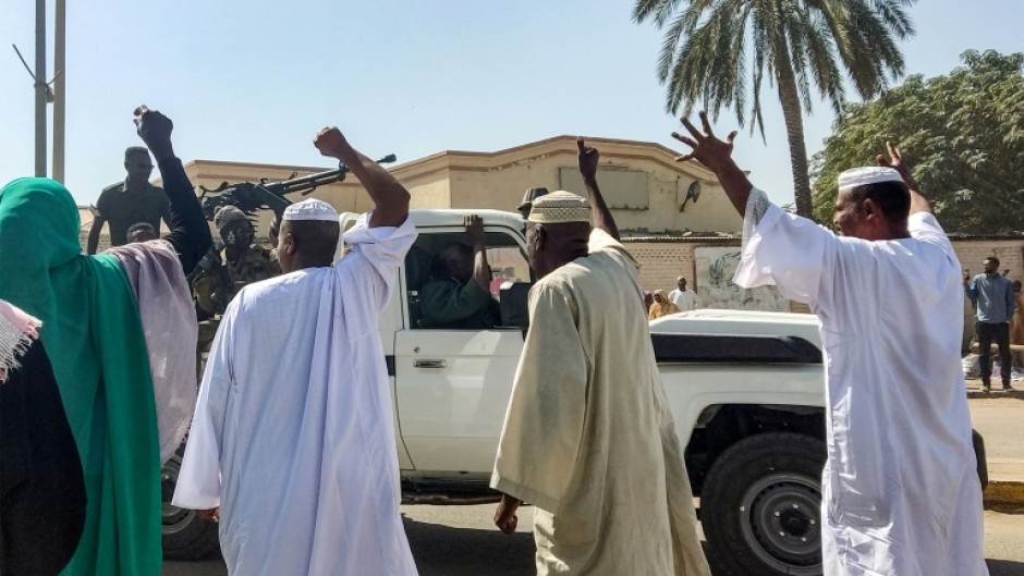 People displaced by the conflict in Sudan cheer as a Sudanese army truck driving by in the city of Gedaref