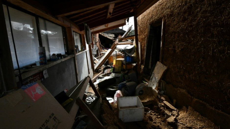 Damaged houses, including one totally collapsed (C), are pictured along a street in Wajima, Japan