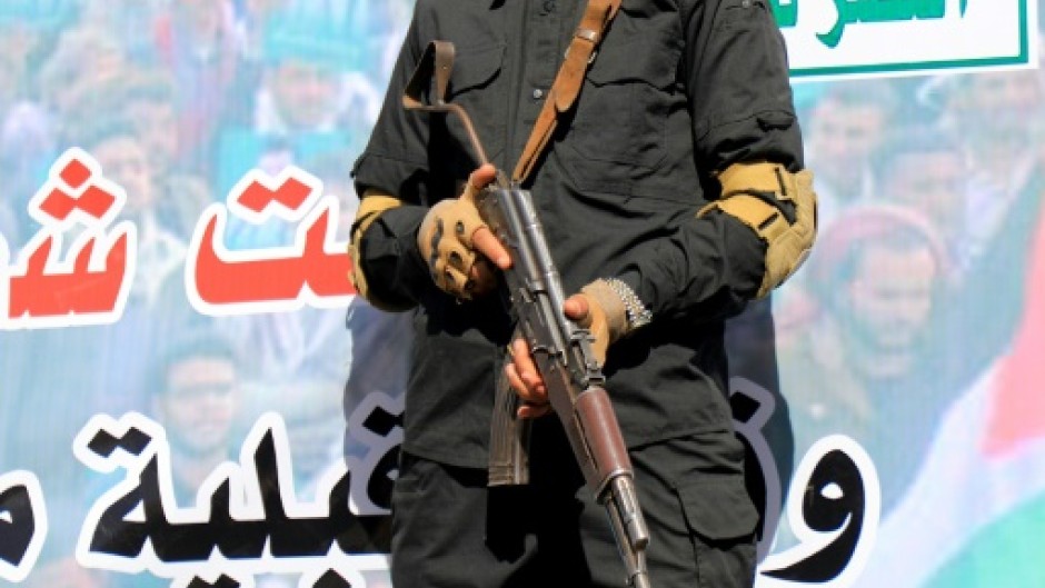 A Huthi fighter in front of a banner which reads in Arabic: 'Death to America, Death to Israel' 