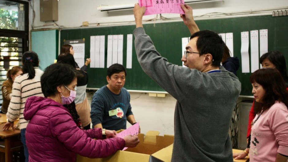 An official of a polling station holds up a ballot slip, as vote counting for the presidential elections commences, at a high school in New Taipei City on January 13, 2024. Vote counting got under way 