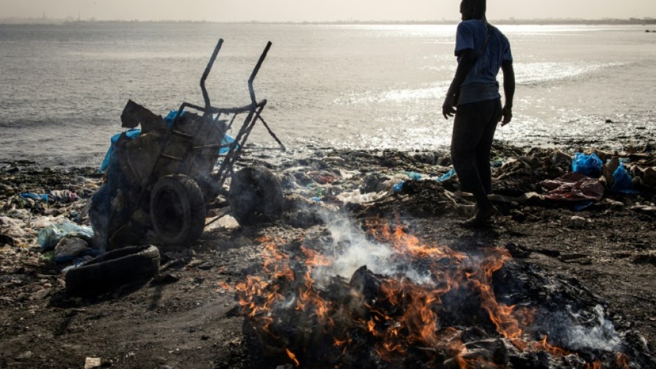 A man dumps waste into the ocean at Hann Bay