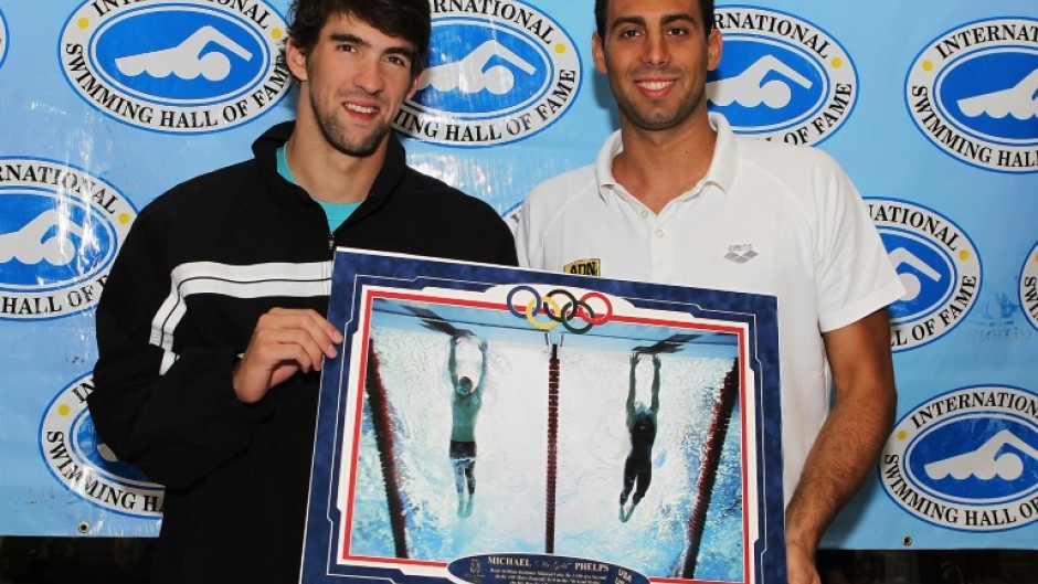 US swim star Michael Phelps, left, and Milorad Cavic hold a famous Sports Illustrated photo of their 100m butterfly photo finish, in which Phelps won gold at the 2008 Olympics, a sign of the iconic nature of the magazine which had its staff fired