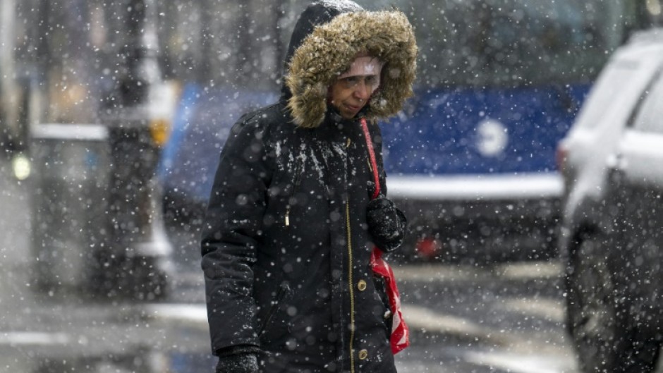 A woman walks as snow falls during a storm in New York City on January 19, 2024, but several parts of the country were getting pummelled by blizzard conditions